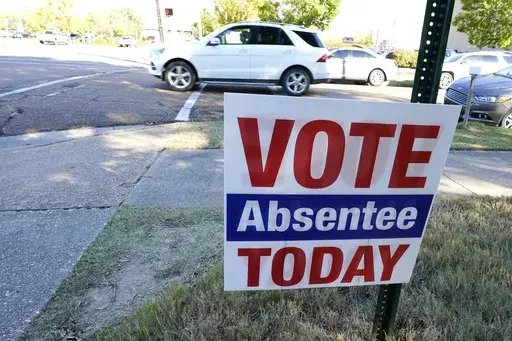 A sign encouraging voters to vote absentee in light of COVID-19 precautions rests on the grounds of the Hinds County Courthouse in Jackson, Miss., Tuesday, Oct. 6, 2020. A federal judge issued an order Tuesday, July 25, 2023, to block a new Mississippi law that would restrict who could help people with absentee voting.(AP Photo/Rogelio V. Solis)