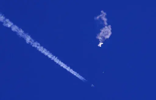 A fighter jet flies past the remnants of a large balloon after it was shot down above the Atlantic Ocean, just off the coast of South Carolina near Myrtle Beach, Feb. 4, 2023. The missile fired by a U.S. F-22 ended the days-long flight of what the Biden administration says was a surveillance operation that took the Chinese balloon near U.S. military sites. It was an unprecedented incursion across U.S. territory for recent decades, and raised concerns among Americans about a possible escalation i