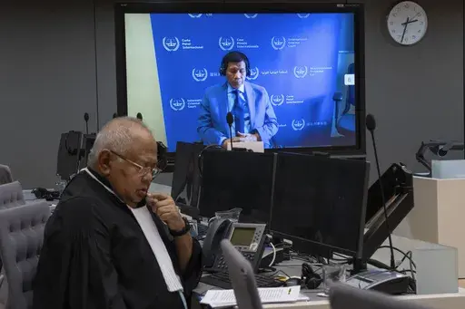 Former Philippine President Rodrigo Duterte is seen on a screen in the courtroom of the International Criminal Court (ICC) with his lawyer Salvador Medialdea seated left, in The Hague, Netherlands, Friday, March 14, 2025. (AP Photo/Peter Dejong, Pool)