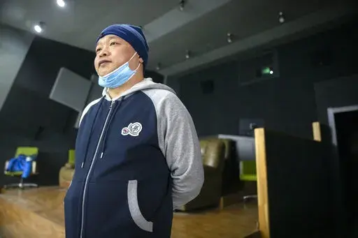 Lan Bo, director of the documentary film "Wuhan, I Am Here," stands in a screening room before a viewing of his movie in Beijing, Saturday, Jan. 15, 2022. The homeless, the sick, the elderly: For people who fell through the cracks of the official system, the then-unprecedented decision to isolate the central Chinese city of Wuhan and its 13 million people was a matter of life or death. Director Lan Bo hopes to sound the alarm with a documentary about volunteers who helped neighbors get food and 