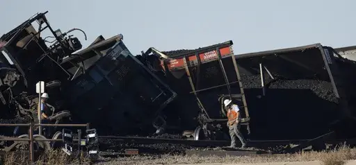Workers toil to clear rail cars that derailed and collapsed a bridge over Interstate 25 northbound, Monday, Oct. 16, 2023, north of Pueblo, Colo. Federal investigators said Thursday they’re looking at BNSF Railway’s inspection and maintenance practices as the investigate the accident that killed a truck driver passing beneath the train. (AP Photo/David Zalubowski, File)