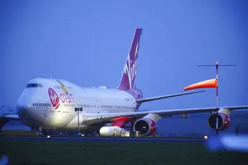 Virgin Atlantic Cosmic Girl, a repurposed Virgin Atlantic Boeing 747 aircraft carrying a rocket, is parked at Spaceport Cornwall, at Cornwall Airport in Newquay, England, Monday, Jan. 9, 2023. Engineers are making final preparations for the first satellite launch from the U.K. later Monday, when a repurposed passenger plane is expected to release a Virgin Orbit rocket carrying several small satellites into space. (Ben Birchall/PA via AP)