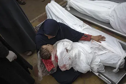 A woman mourns the bodies of her child and her husband killed in an Israeli army bombardment of the Gaza Strip, in the hospital in Khan Younis, Tuesday Dec. 5, 2023. (AP Photo/Fatima Shbair)