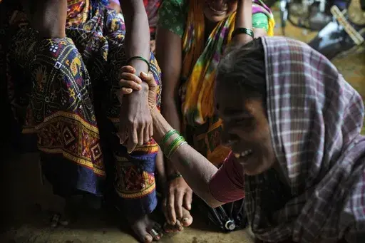 A woman holds the hand of her relative as family members of people trapped under rubble wail after a landslide washed away houses in Raigad district, western Maharashtra state, India, July 20, 2023. The devastation of this year's monsoon season in India, which runs from June to September, has been significant. (AP Photo/Rafiq Maqbool)