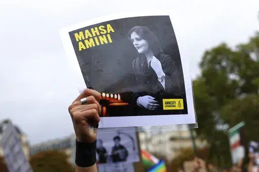A protester shows a portrait of Mahsa Amini during a demonstration to support Iranian protesters standing up to their leadership over the death of a young woman in police custody, Sunday, Oct. 2, 2022 in Paris.  Anti-government demonstrations erupted Saturday, Oct. 8,  in several locations across Iran as the most sustained protests in years against a deeply entrenched theocracy entered their fourth week. The protests erupted Sept. 17, after the burial of 22-year-old Amini, a Kurdish woman who ha