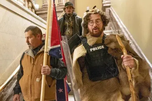 FILE — Supporters of President Donald Trump, including Aaron Mostofsky, right, who is identified in his arrest warrant, walk down the stairs outside the Senate Chamber in the U.S. Capitol, in Washington, Jan. 6, 2021. Mostofsky, the son of a New York judge, who referred to himself as a "caveman" eager to protest Donald Trump's presidential election loss, was sentenced on Friday, May 6, 2022, to eight months in prison. U.S. District Judge James Boasberg told Mostofsky that he was "literally on 