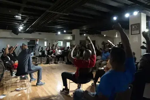 Panelists and attendees raise their fists during a Black Man Lab meeting to discuss the candidacy of Vice President Kamala Harris, Monday, July 22, 2024, in Atlanta. (AP Photo/Stephanie Scarbrough)
