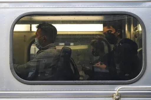 People wear face masks as they sit in a Metra train at the Metra Arlington Heights station Thursday, Sept. 15, 2022, in Arlington Heights, Ill. President Joe Biden said Thursday a tentative railway labor agreement has been reached, averting a potentially devastating strike before the pivotal midterm elections. (AP Photo/Nam Y. Huh)