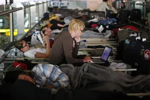 Passengers waiting for a flight to Helsinki rest at Lisbon's international Portela Airport on May 10, 2010, as flights were disrupted due to an ash cloud drifting over from a volcano in Iceland that caused major air travel chaos. (AP Photo/Francisco Seco, File)