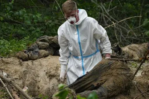 A member of an extraction crew works during an exhumation at a mass grave near Bucha, on the outskirts of Kyiv, Ukraine, Monday, June 13, 2022. (AP Photo/Natacha Pisarenko)