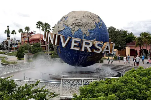 Guests cool off under a water mist by the globe at Universal Studios City Walk at Universal Studios Florida in Orlando, Fla., Aug. 5, 2019. (AP Photo/John Raoux, File)
