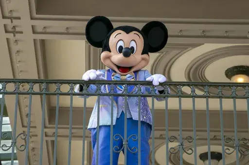 An actor dressed as Mickey Mouse greets visitors at the entrance to Magic Kingdom Park at Walt Disney World Resort, April 18, 2022, in Lake Buena Vista, Fla. Winnie the Pooh and Mickey Mouse have recently entered the public domain, making it possible for artists to use them freely. (AP Photo/Ted Shaffrey, File)