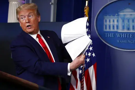 FILE President Donald Trump holds up papers as he speaks about the coronavirus in the James Brady Press Briefing Room of the White House on April 20, 2020, in Washington. Revelations that Trump took government records with him to Mar-a-Lago is a political headache for the former president and a potential legal one too. House investigators have launched an investigation, and the National Archives and Records Administration has reportedly asked the Justice Department to look into the matter. (AP P