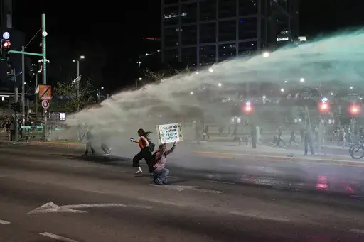 Police use water cannon to disperse demonstrators blocking a road during a protest against Israeli Prime Minister Benjamin Netanyahu's government, and calling for the release of hostages held in the Gaza Strip by the Hamas militant group, in Tel Aviv, Israel, Saturday, May 18, 2024. (AP Photo/Leo Correa)