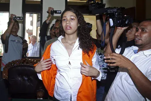Heather Mack of Chicago, Ill., center, is mobbed by reporters as she arrives in the courtroom for her sentencing hearing at a district court in Denpasar, Bali, Indonesia, April 21, 2015. The Chicago woman facing federal conspiracy charges in the 2014 killing of her mother during a luxury vacation in Bali plans to plead guilty, her attorney said Thursday, June 1, 2023. (AP Photo/Firdia Lisnawati, File)