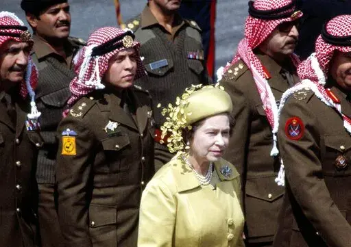 Britain's Queen Elizabeth II, stands in front of Abdullah, who would later become king, with members of the Jordanian Army on her arrival for a State Visit, in Amman, Jordan, March 27 1984. Not long after Queen Elizabeth II inherited her throne, large swaths of the world broke free from British control. Yet today after her death, British-installed monarchies still reign over millions across the Middle East. (AP Photo/Saade, File)