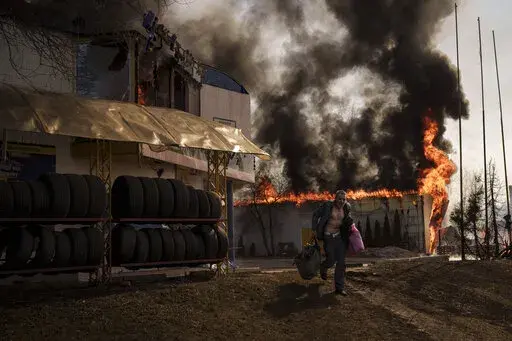 A man runs after recovering items from a burning shop following a Russian attack in Kharkiv, Ukraine, Friday, March 25, 2022. (AP Photo/Felipe Dana)