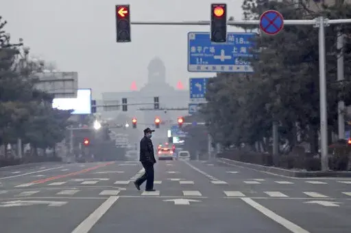 A man walks across an empty road during the fourth day of a city wide lock down in Changchun in northeastern China's Jilin province Monday, March 14, 2022. China banned most people from leaving the coronavirus-hit northeastern province and mobilized military reservists Monday as the fast-spreading "stealth omicron" variant fuels the country's biggest outbreak since the start of the pandemic two years ago. (Chinatopix Via AP) CHINA OUT