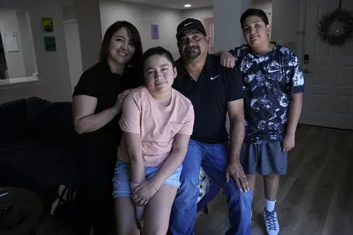 Mayah Zamora, second from left, a survivor of the mass shooting at Robb Elementary in Uvalde, Texas, poses for a photo with her mom Christina, left, dad Ruben, and brother Zach, right, at their home in San Antonio, Tuesday, June 27, 2023. Besides medical bills and the weight of trauma and grief, mass shooting survivors and their family members contend with scores of other changes that show how thoroughly their lives have been upended by violence. (AP Photo/Eric Gay)