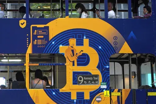 An advertisement for the cryptocurrency Bitcoin displayed on a tram, May 12, 2021, in Hong Kong. Sometime in the next few days or even hours, the “miners” who chisel bitcoins out of complex mathematics are going to take a 50% pay cut — effectively slicing new emissions of the world’s largest cryptocurrency in an event called bitcoin halving. (AP Photo/Kin Cheung, File)