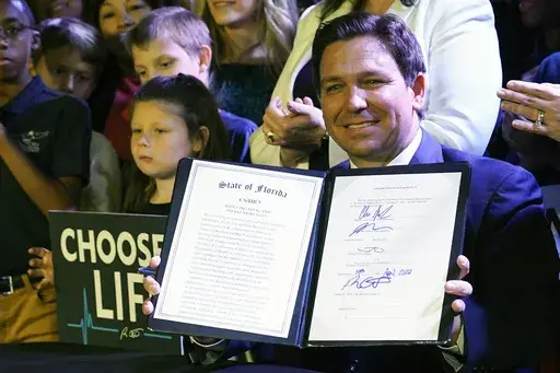Florida Gov. Ron DeSantis holds up a 15-week abortion ban law after signing it on April 14, 2022, in Kissimmee, Fla. (AP Photo/John Raoux, File)