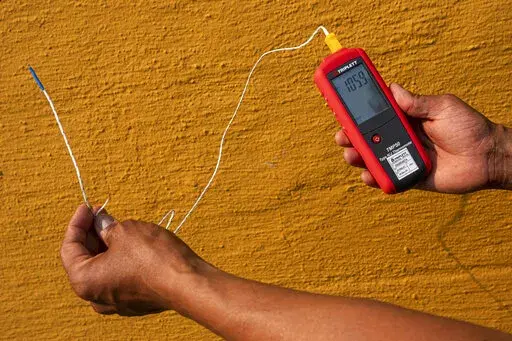 Vivek Shandas, a professor of climate adaptation at Portland State University, takes a temperature reading of almost 106 degrees in downtown Portland, Ore., on Aug. 12, 2021. On Thursday, Jan. 13, 2022, NASA and the National Oceanic and Atmospheric Administration released measurements showing 2021 was the sixth hottest year on record globally, part of a long-term warming trend. (AP Photo/Nathan Howard, File)
