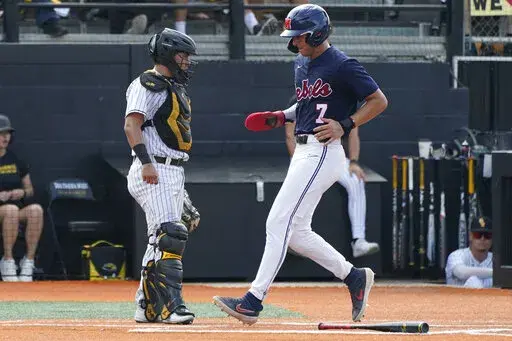 Southern Mississippi catcher Rodrigo Montenegro stands near the plate as Mississippi's Jacob Gonzalez scores during the third inning of an NCAA college baseball tournament super regional game Saturday, June 11, 2022, in Hattiesburg, Miss. (AP Photo/Rogelio V. Solis)