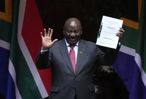FILE — South African President Cyril Ramaphosa shows the signed bill for National Health Insurance signed into law in Pretoria, South Africa, Wednesday, May 15, 2024. Several polls have the African National Congress' support below 50% ahead of next Wednesday's, May 29, 2024 vote, raising the prospect that it might not be the majority party for the first time since Nelson Mandela led it to victory in the first all-race elections that ended white minority rule in 1994. (AP Photo/Themba Hadebe, F