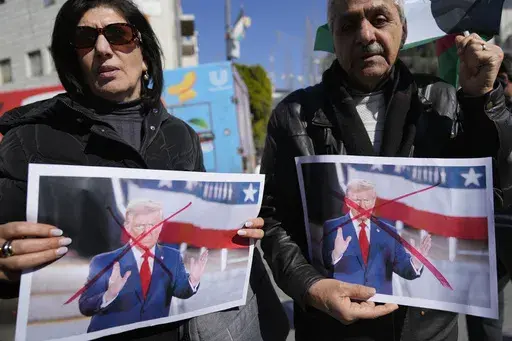 Palestinians carry defaced pictures of U.S. President Donald Trump while protesting against his latest statements regarding the transfer of Palestinians from Gaza, in the West Bank city of Ramallah Wednesday, Jan. 29, 2025. (AP Photo/Nasser Nasser)