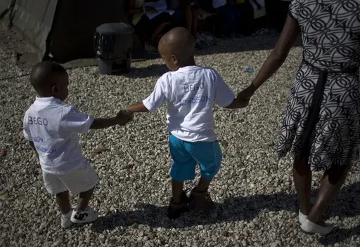 Haitian children walk hand in hand as they await the arrival of their adoptive parents in Port-au-Prince, Haiti, Dec. 21, 2010. (AP Photo/Ramon Espinosa, File)