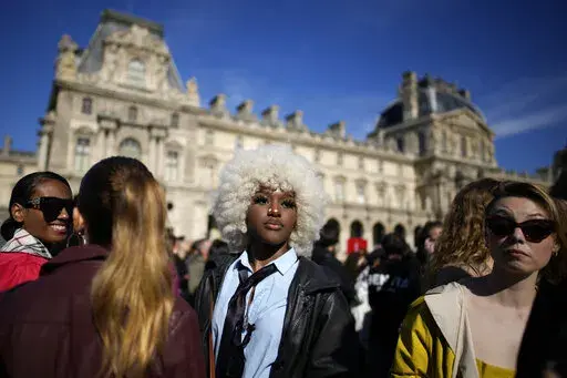 Fashion lovers wait in the courtyard of the Louvre museum during Louis Vuitton ready-to-wear Spring/Summer 2023 fashion collection presented Tuesday, Oct. 4, 2022 in Paris. (AP Photo/Christophe Ena)