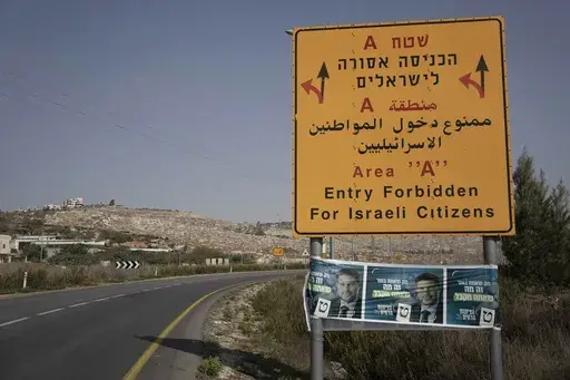 Campaign posters for far-right Israeli lawmaker Bezalel Smotrich, now the Minister of Finance, are strung across a road sign marking an entrance to an area under Palestinian control, near the West Bank town of Nablus, Sunday, Oct. 16, 2022. Smotrich assumed new powers from the military over the occupied territory this year. As the first minister to oversee civilian life in the West Bank, his role amounts to a recognition that Israel's occupation is not temporary, but permanent, observers say. (A