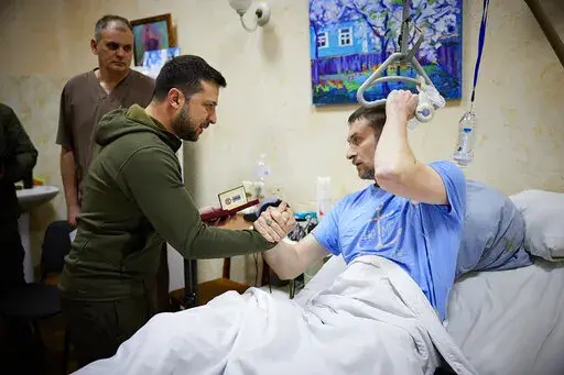 In this photo provided by the Ukrainian Presidential Press Office on Sunday, March 13, 2022, President Volodymyr Zelenskyy, center, shakes hands with a wounded soldier during his visit to a hospital in Kyiv, Ukraine. (Ukrainian Presidential Press Office via AP)