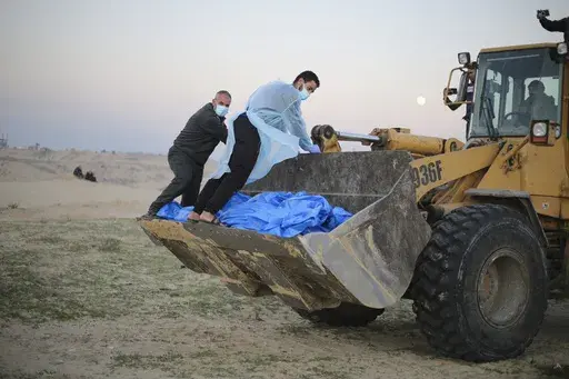 Bulldozer carries the bodies of Palestinians killed in the north of the Gaza Strip and turned over by the Israeli military during a mass funeral in Rafah, Tuesday, Dec. 26, 2023. (AP Photo/Hatem Ali)