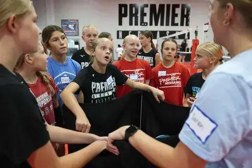 Lily Borgmann, 11, center, huddles with her team between drills at Premier Nebraska Volleyball, Monday, Aug. 19, 2024, in Omaha, Neb. (AP Photo/Rebecca S. Gratz)