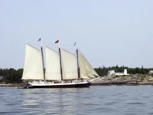 The Schooner Victory Chimes sails past the Pemaquid Point Light in Bristol, Maine, June 24, 2003. The 123-year-old schooner that was once declared the “Official Windjammer of Maine” by state lawmakers has new owners, and will be leaving Maine. (AP Photo/Annie Higbee, File)
