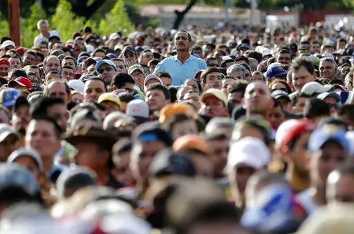 A man peaks over the crowd waiting on the Simon Bolivar bridge to cross the border into Colombia, to hunt for food and medicine in San Antonio del Tachira, Venezuela, July 17, 2016. Over the last 10 years, more than 7.1 million people have left Venezuela amid a political, economic and humanitarian crisis that has marked the entirety of President Nicolas Maduro’s government. (AP Photo/Ariana Cubillos, File)