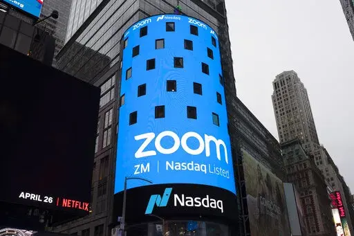 This April 18, 2019, file photo shows a sign for Zoom Video Communications ahead of the company's Nasdaq IPO in New York. The video-conferencing service is cutting about 1,300 jobs, or approximately 15% of its workforce. CEO Eric Yuan said in a blog post Tuesday, Feb. 7, 2023, that the company ramped up staffing during the COVID-19 pandemic, when businesses became increasingly reliant on its service as people worked from home. Yuan said Zoom grew three times in size within 24 months to manage de