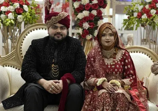Pakistani bride Dua Khan and groom Asher Khan pose for photo during their wedding ceremony at Radiance banqueting hall, in Karachi, Pakistan, Saturday, Jan. 27, 2024. There's a scrum of people trying to get photos with the married couple at the Radiance banqueting hall in a middle-class Karachi neighborhood Voices are barely audible above the din of 400 guests, dinner service, music, and the drone whirring around the room. The bride and groom are beaming. Their families and friends jostle for a 
