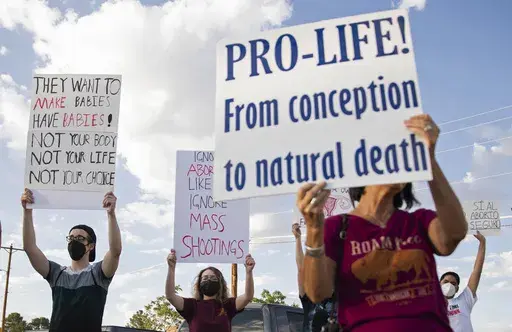 An anti-abortion advocate along with abortion rights advocates hold up signs during the Emergency Pro-Life Rally for New Mexico in Las Cruces, N.M., July 19, 2022. The New Mexico Supreme Court blocked local anti-abortion ordinances Friday, March 31, 2023, pending the outcome of a case centered on constitutional rights to equal protection and due process. (Meg Potter/The Las Cruces Sun News via AP, File)