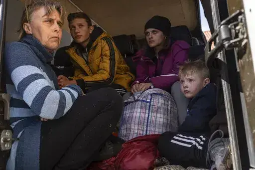 Oksana Gavrielutca 41, from left, sits at the back of a bus with her children Oleg 18, Diana, 17, and Vlad, 5, after they fled from Snigiriovka village, in Mikolaiv district, Ukraine, on Thursday, April 7, 2022. (AP Photo/Petros Giannakouris)