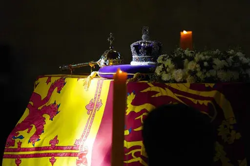 FILE A ray of sun shines on the coffin of Queen Elizabeth II, draped in the Royal Standard with the Imperial State Crown and the Sovereign's orb and sceptre, during it's lying in state on the catafalque in Westminster Hall, at the Palace of Westminster, in London, Saturday, Sept. 17, 2022.  When Queen Elizabeth II’s grandfather, King George V, died in 1936, life in Britain is unrecognizable to people today. But despite almost a century of change, the images from the queen’s lying in state th