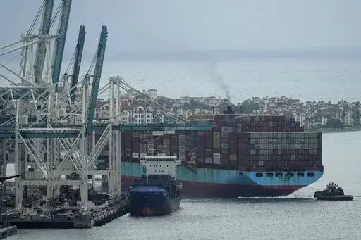 Tugboats guide the Axel Maersk container ship as it arrives into port, Oct. 21, 2021, in Miami. The marine shipping industry is facing new regulations to address carbon pollution. Its trade groups have been seeking exemptions for pollution emitted during voyages on rough seas. (AP Photo/Rebecca Blackwell, File)