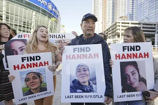 Ryan Kobayashi, center, holds a picture of his missing daughter Hannah Kobayashi outside Crypto.com Arena, Thursday, Nov. 21, 2024 in Los Angeles. (AP Photo/Damian Dovarganes, File)