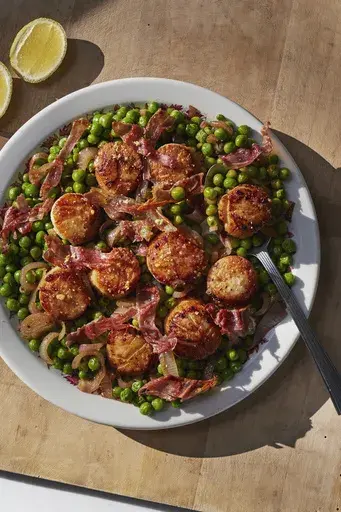 This image released by Weldon Owen shows a recipe for scallops with peas and prosciutto from the cookbook "Out There: A Camper Cookbook: Recipes from the Wild" by Lee Kalpakis. (Brittany Barb/Weldon Owen via AP)