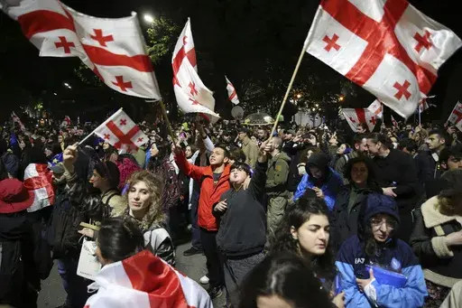 Demonstrators waving Georgian national flags gather in front of the Parliament building during an opposition protest against "the Russian law" in the center of Tbilisi, Georgia, early Monday, May 13, 2024. Daily protests are continuing against a proposed bill that critics say would stifle media freedom and obstruct the country's bid to join the European Union. (AP Photo/Zurab Tsertsvadze)