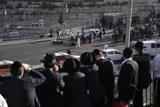 People look at Israeli police officers and volunteers from the Zaka rescue service work at the shooting attack in Jerusalem, Thursday, Nov. 30, 2023. The shooting death of an Israeli man who raced to confront Palestinian attackers has raised questions about the use of excessive force among Israeli security forces and the public. The man's shooting mirrors previous incidents where Israeli security forces or civilians have opened fire on attackers who no longer appear to pose a threat or on suspec
