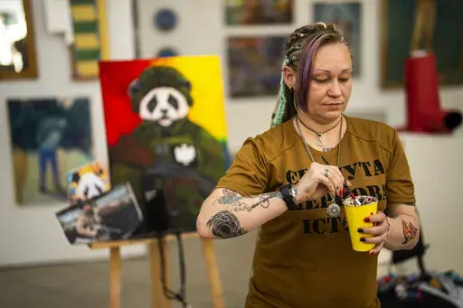 Ukrainian Anastasiya Sereda paints a canvas in an art class for women bereaved by war, in Kyiv, Ukraine, Sunday, April 28, 2024. (AP Photo/Francisco Seco)