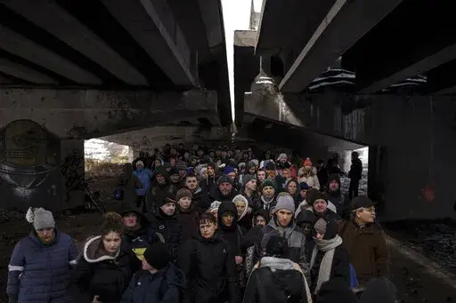 People crowd under a destroyed bridge as they try to flee, crossing the Irpin river on the outskirts of Kyiv, Ukraine, Tuesday, March 8, 2022. Russia's relentless digital assaults on Ukraine may have caused less damage than many anticipated. But most of its hacking is focused on a different goal that gets less attention but has chilling potential consequences: data collection. (AP Photo/Felipe Dana, File)