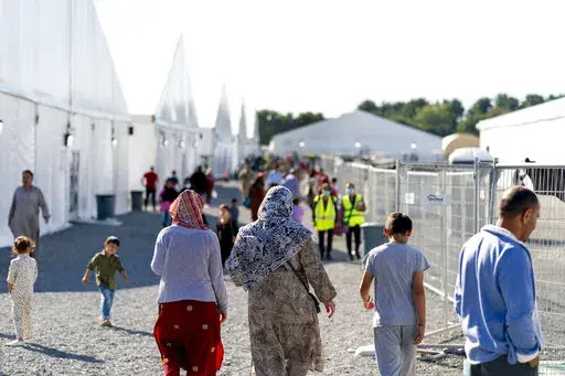 Afghan refugees walk through an Afghan refugee camp at Joint Base McGuire Dix Lakehurst, N.J., on Sept. 27, 2021. Thousands of refugees who fled Afghanistan and now live in the United States are facing an uncertain future. Congress has failed so far to create a pathway to residency for Afghans who came to America after working alongside U.S. soldiers in the war. (AP Photo/Andrew Harnik, File)